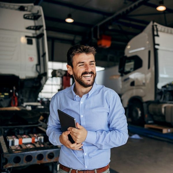 Smiling man with tablet in front of trucks