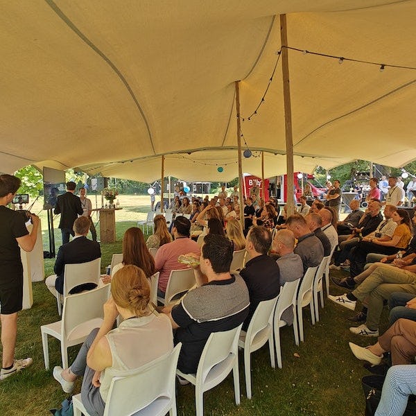 Toehoorders zitten onder een tent en luisteren naar een presentatie tijdens het Trend Festival